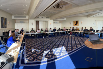 Bilde av forsamling mennesker i et stort møterom.